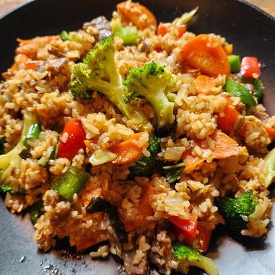 Fried rice with broccoli, carrots and red peppers on a dark plate