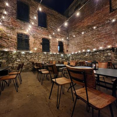 RameNesque patio at night with brick walls, string lights, tables and chairs