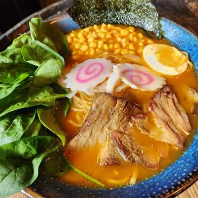 Bowl of ramen with sliced pork, corn, narutomaki, a soft-boiled egg, spinach and nori
