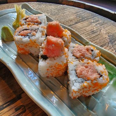 Tuna sushi roll coated in orange fish roe on a green plate