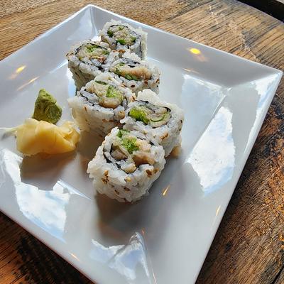 Sushi roll pieces on a white plate with pickled ginger and wasabi