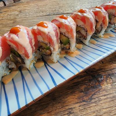Row of sushi pieces topped with raw tuna and spicy mayo on a blue-striped plate