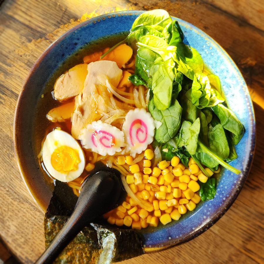 Bowl of ramen with narutomaki, corn, spinach and noodles in a rich broth