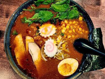 Dan Dan ramen with spicy ground chicken, corn, spinach and a halved egg in a red broth